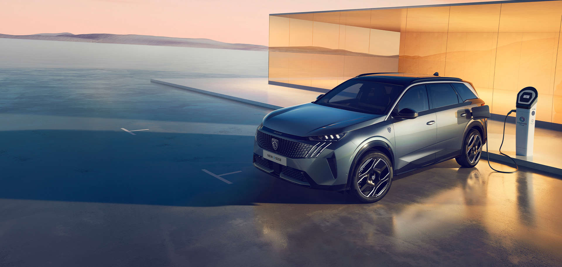 Peugeot e-5008 синього кольору заряджається від електромережі, вигляд спереду з лівого боку